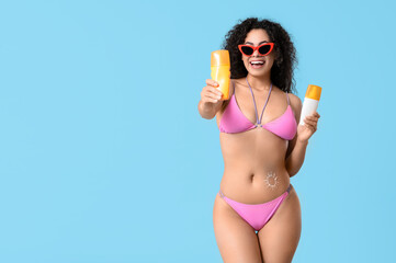 Beautiful young African-American woman in swimsuit with sun made of sunscreen cream on her belly...