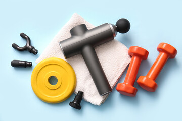 Composition with percussive massager, nozzles, clean towel and sports equipment on color background