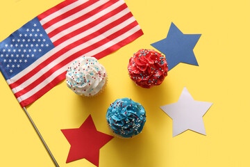 Tasty patriotic cupcakes with USA flag and stars on yellow background. American Independence Day