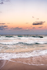 sunset over ocean with waves crashing on beach