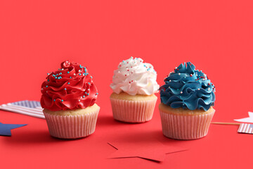 Tasty patriotic cupcakes with USA flags and stars on red background. American Independence Day