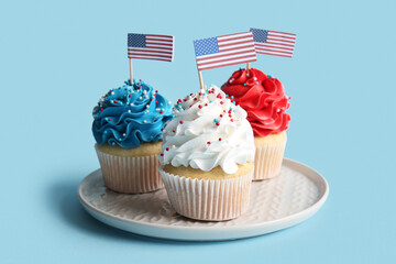 Tasty patriotic cupcakes with USA flags on blue background. American Independence Day