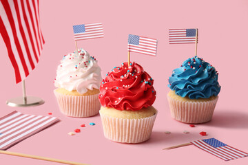 Tasty patriotic cupcakes with USA flags on pink background. American Independence Day