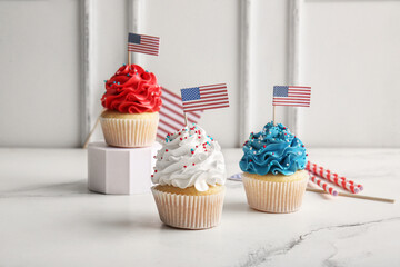 Tasty patriotic cupcakes with USA flags on white table. American Independence Day