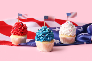Tasty patriotic cupcakes with USA flags on pink background. American Independence Day