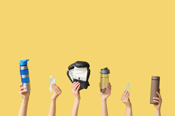 Female hands with water bottles, light blue ribbon, boxing gloves and male sign on yellow background. Prostate cancer concept