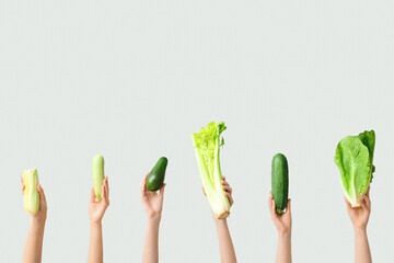 Female hands holding fresh vegetables on grey background