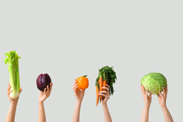 Female hands holding fresh vegetables on grey background