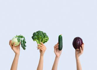 Female hands holding fresh vegetables on white background