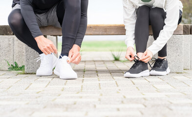 靴紐を結んで運動の準備をするアジア人の男女
