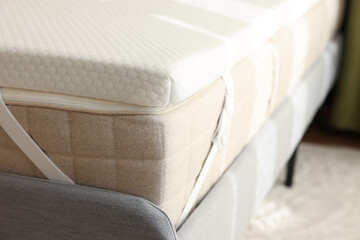 White memory foam mattress topper on grey bed, closeup