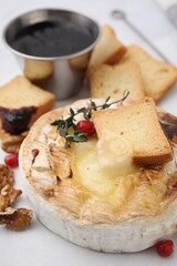 Tasty baked camembert with crouton, thyme, walnuts and pomegranate seeds on white table, closeup