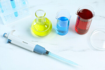 Laboratory analysis. Micropipette, petri dish and other glassware on white marble table