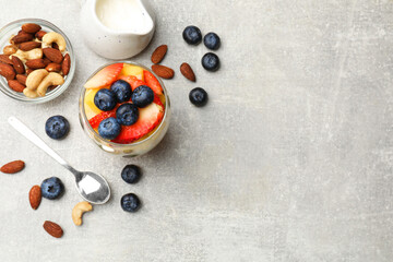 Delicious fruit salad, fresh berries and nuts on light grey table, flat lay. Space for text