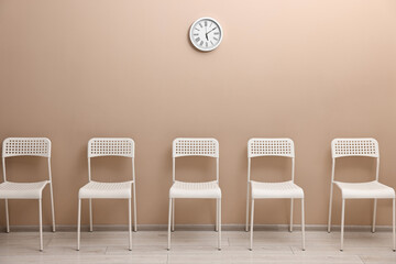 Many chairs near beige wall in waiting area indoors