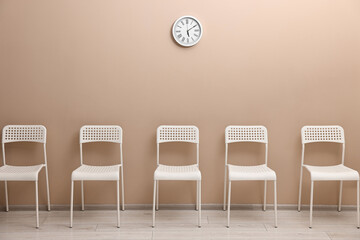 Many chairs near beige wall in waiting area indoors