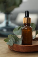 Aromatherapy. Bottle of essential oil and eucalyptus leaves on wooden table