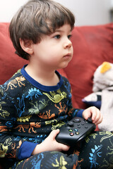 cute boy with a game pad playing on the couch