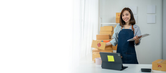 A woman in a blue apron stands in front of a stack of boxes