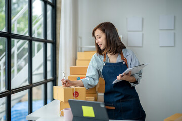 A woman is sitting at a desk with a laptop and a clipboard