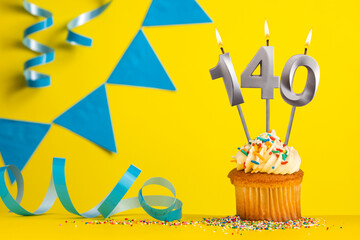 Lighted birthday candle number 140 - Yellow background with blue pennants