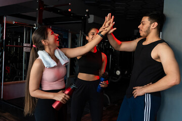 Group of fit indian friends give high five in gym. Mindful happy sporty people celebrating success...