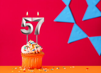 Birthday cupcake with candle number 57 on a red background with blue pennants