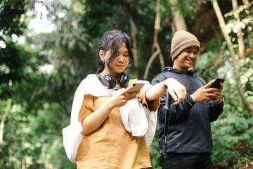 Two Young Couple Hiking at The Mountain Having Conversation While Holding Smartphone to Update Social Media. 