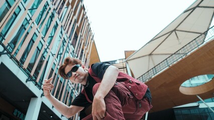 Low angle of asian attractive hipster pose at camera surround by mall. Portrait of break dance choreographer looking at camera while dancing in hip hop style. Outdoor sport 2024. Endeavor.