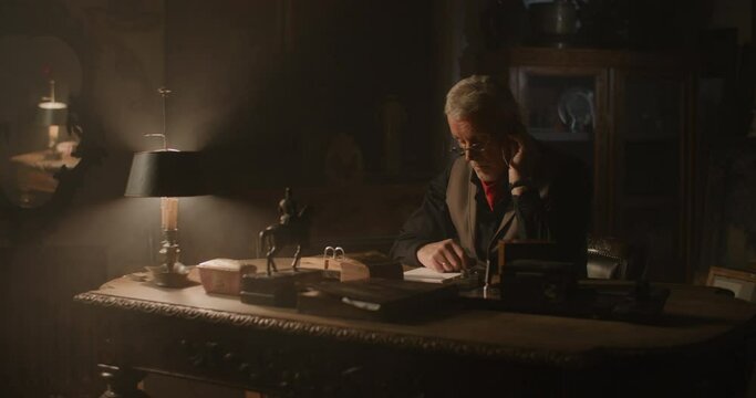 Old watchmaker working in his vintage store.