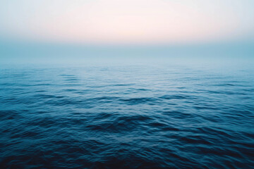 Endless ocean under a hazy sky at dawn, capturing the peaceful, misty atmosphere of the sea blending into the horizon.