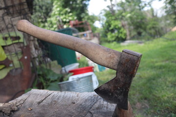 Used Ax hatchet stuck in a wood stump, in courtyard, countryside area