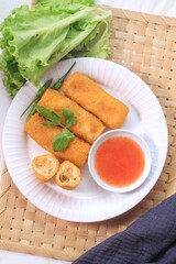 vegetables risoles or risol sayur or risoles sayur stuffed with veggies and enclosed in crepe-like wrappers and rolled into bread crumbs and fried. served on white plate and chili. top view
