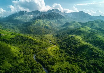 Aerial view of lush, green mountainous landscape with river winding through valleys under a majestic, blue sky with scattered clouds.