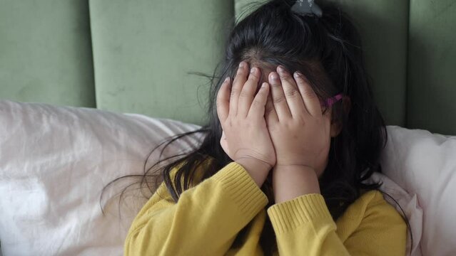 a upset child girl cover her face with hand 