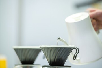 Barista pouring hot water over coffee grounds in a filter.