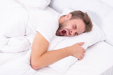 Yawning early in the morning. Asleep young man sleeping. Resting peacefully in comfortable bed....
