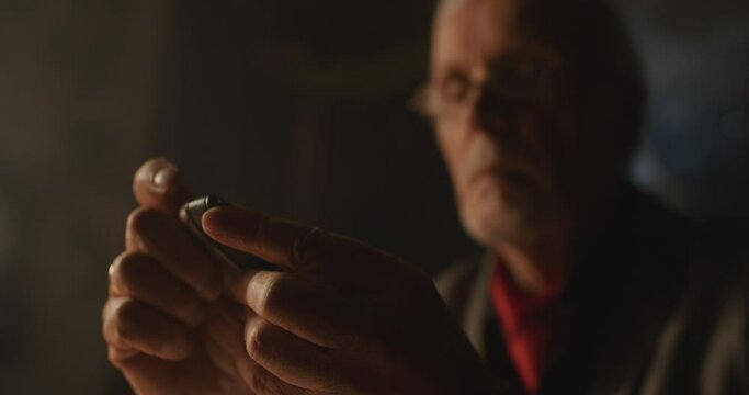 Wise old watchmaker in his office at night.