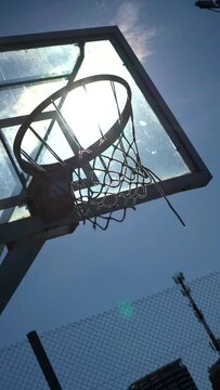 Aro de basquet, baloncesto, en cancha al aire libre, a contraluz del solTiro al aro y erra.