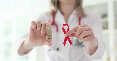 HIV text on cubes in medical clinic and doctor and holding red ribbon