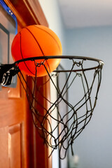 Selective focus on the netting of a miniature toy basketball hoop on the door of a bedroom. © Lost_in_the_Midwest