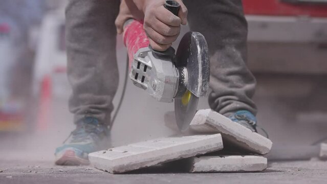 Trabajador corta una baldosa con una amoladora o radial. Herramienta de corte, Construcci&oacute;n y refacci&oacute;n. 