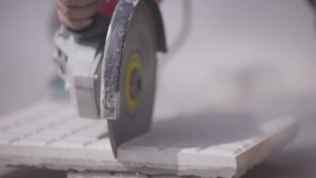 Trabajador corta una baldosa con una amoladora o radial. Herramienta de corte, Construcci&oacute;n y refacci&oacute;n. 