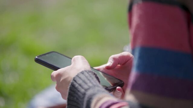 Mano de mujer usando tel&eacute;fono celular al aire libre