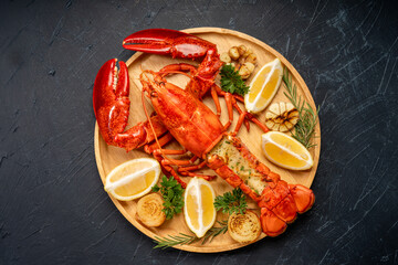 Grilled Lobster with Cheese in black wood plate on wooden background.
