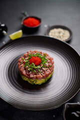 Tuna and avocado tartare on a dark ceramic plate