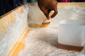Brushing solution through fiberglass sheets on a wooden box. A diy project at home.
