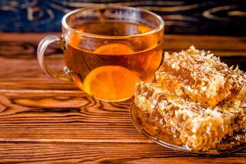 honey in honeycombs and a mug of tea on a brown wooden background
