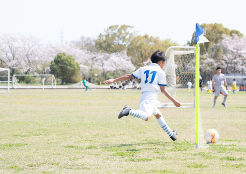 サッカーの試合でコーナーキックを蹴る小学生の男の子