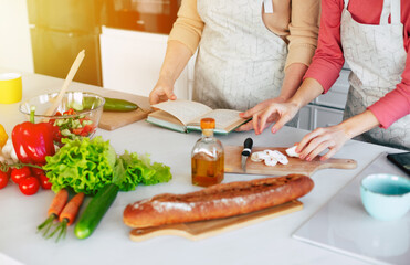 Close up photo of female hands preparing vegan salad. Lady in gray apron making healthy dinner, woman cooks delicious meal at home, cutting vegetables on chopping board, kitchen interior